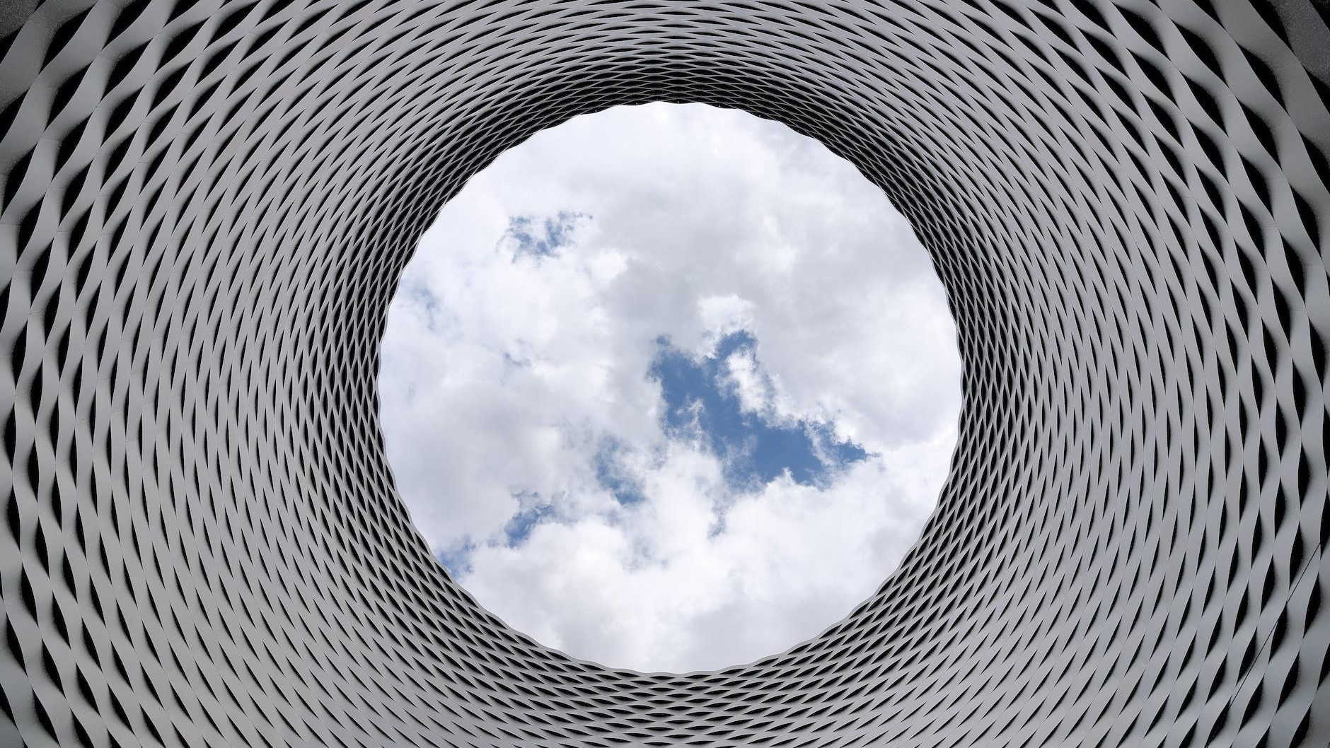 low angle photography of grey and black tunnel overlooking white cloudy and blue sky